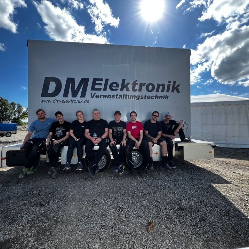 DM Elektronik Team vor einem Anhänger sitzend
